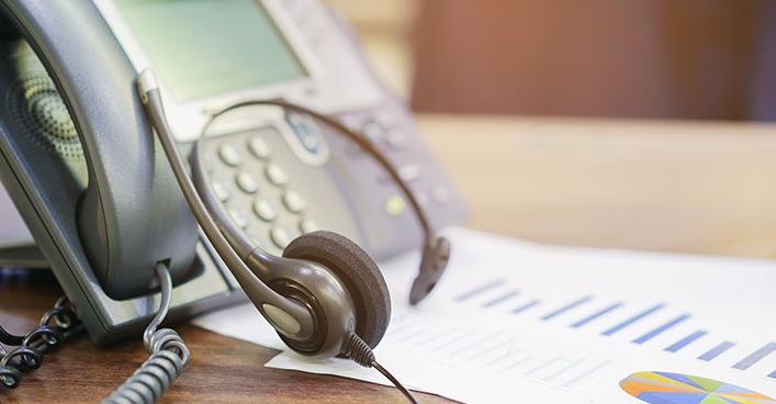 Modern IP desk phone connected to office network beside business laptop